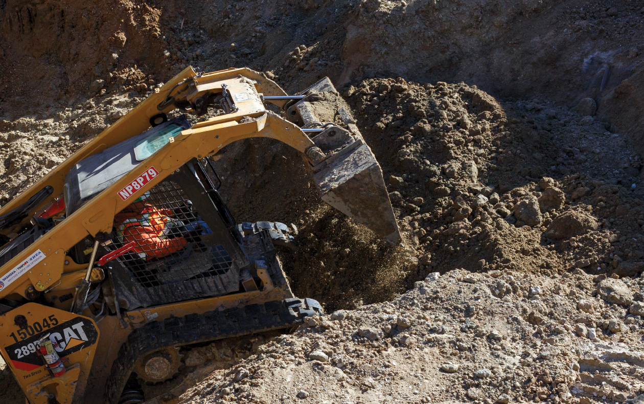 Photo of a Skid Steer Loader picking up soil.