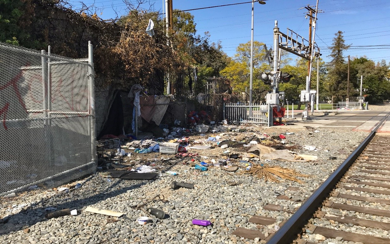 Photo of trash and other refuse sitting adjacent to train tracks
