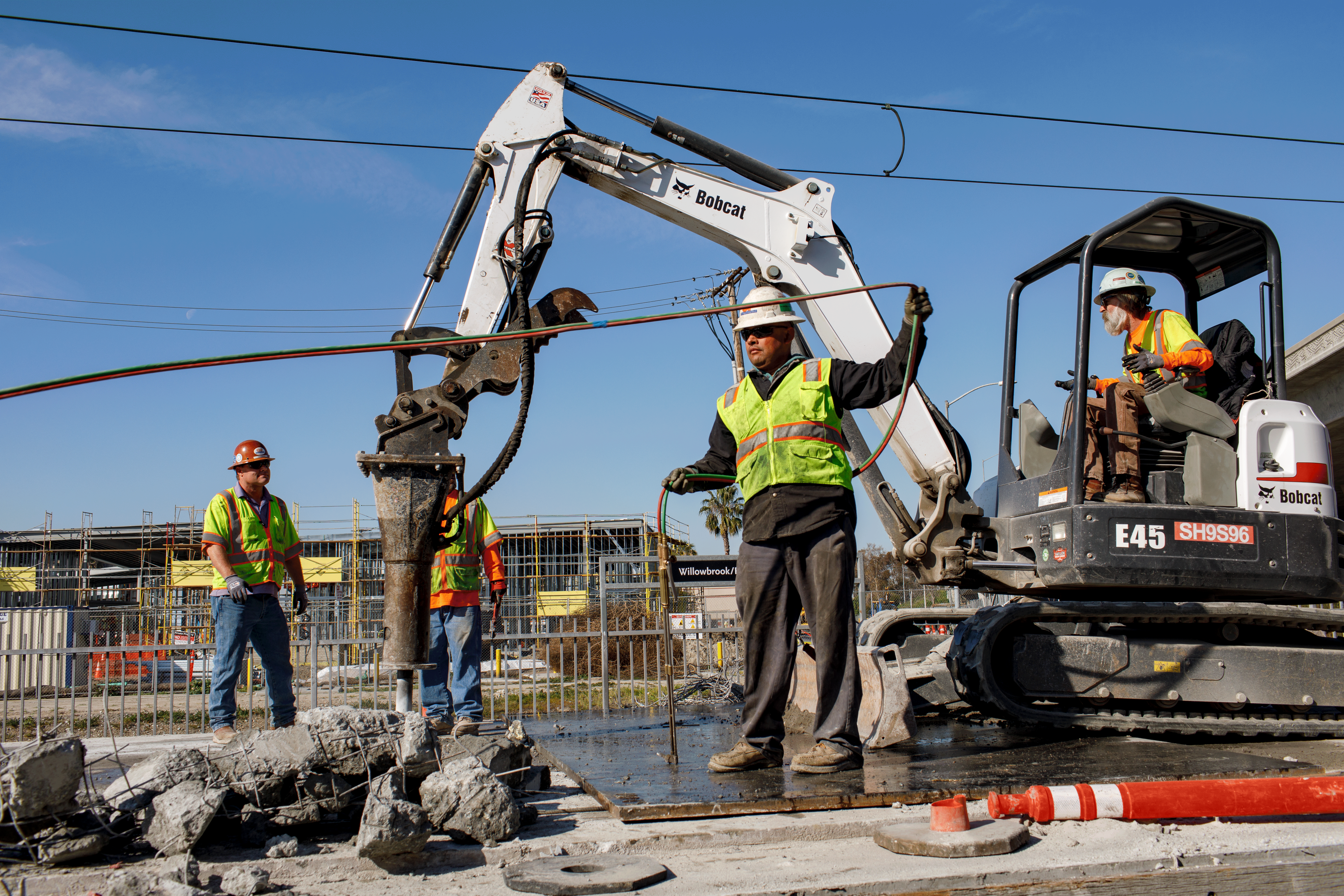 Photo of a contractor leaning over and using an electric saw to cut stone at a construction site.