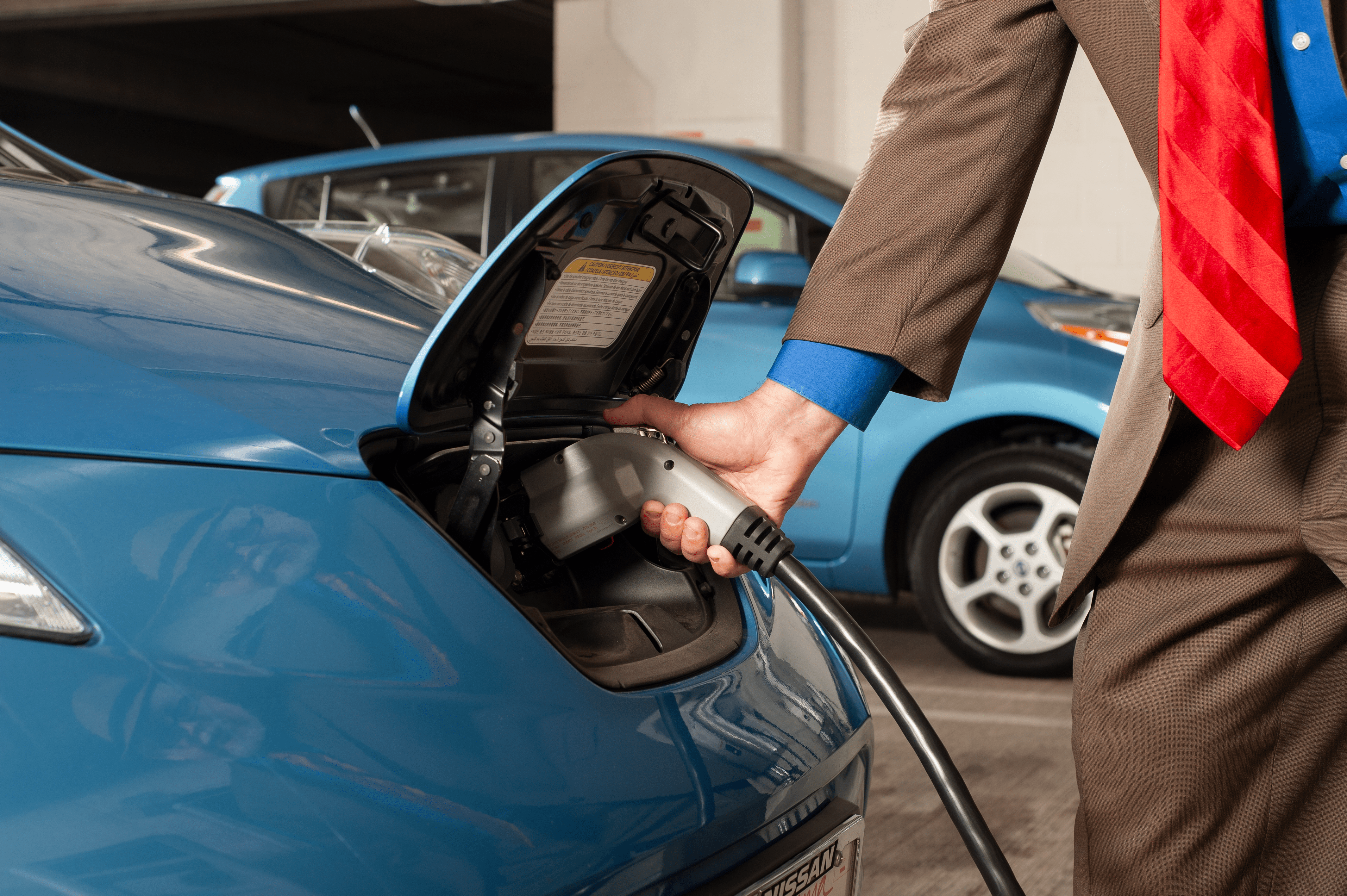 Photo of someone plugging an EV charger into a blue car.